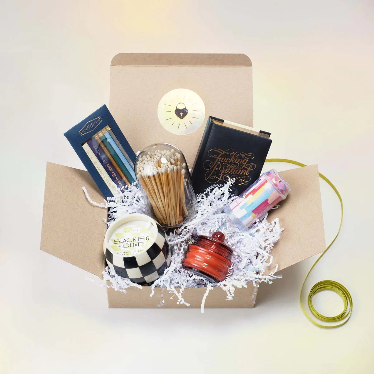 Opened gift box showcasing matches, candles, journal, and pencils as example product