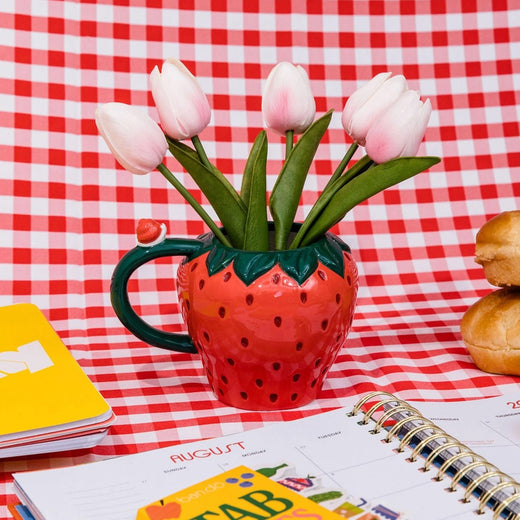 Tulips inside a Strawberry shaped coffee cup with a picnic blanket background