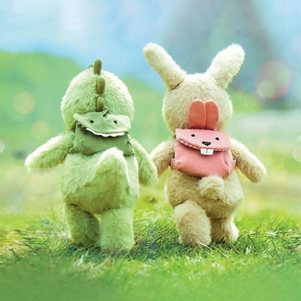 a stuffed dino and stuffed rabbit walk hand in hand on grass