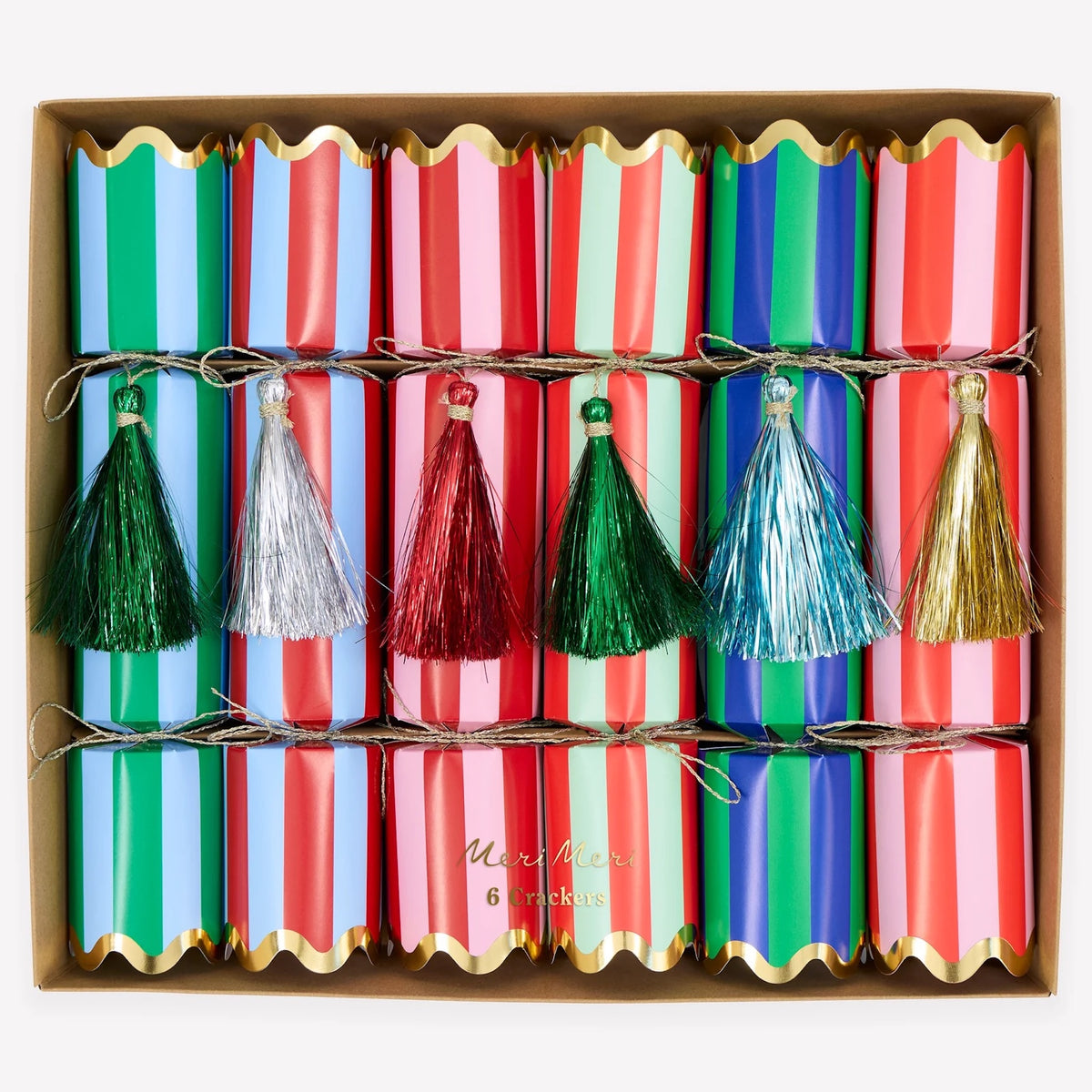 A boxed set of six Christmas paper cracker fireworks with colorful striped wrappers in green, blue, pink, and red, decorated with metallic tassel pulls in green, silver, red, blue, and gold.