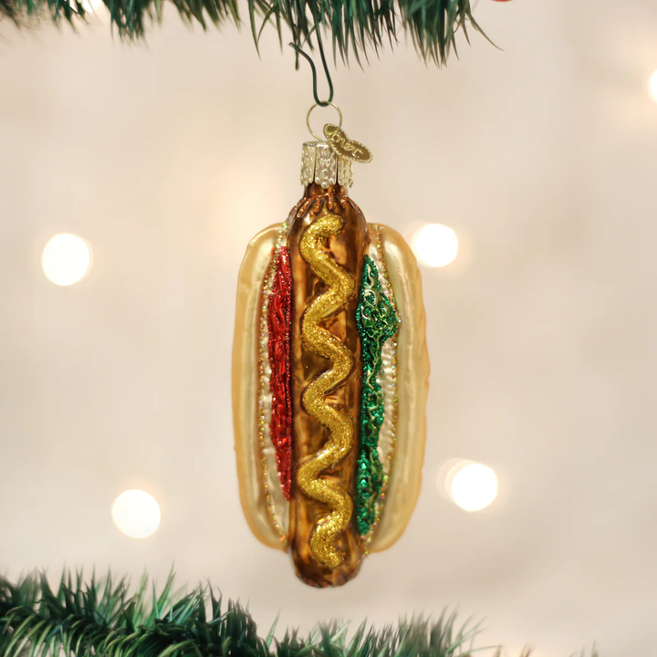 Hot dog ornament hanging on a Christmas tree with lights in the background