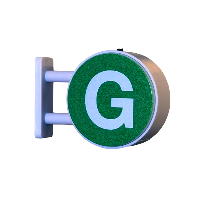A circular green sign with a large white letter G, mounted on a white bracket against a plain white background.