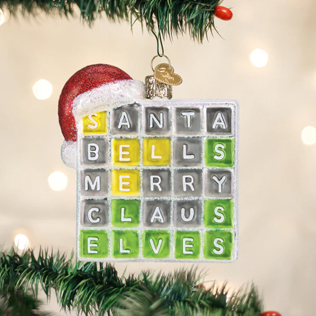Christmas ornament with a crossword-style design featuring Christmas-themed words, hanging on a tree.