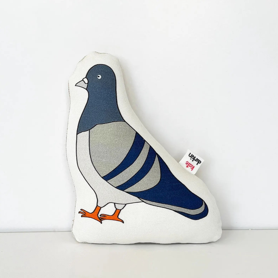 Small bird-shaped throw pillows featuring a stylized pigeon design with a navy blue head, gray body, white wings, and orange feet, set against a plain white background.