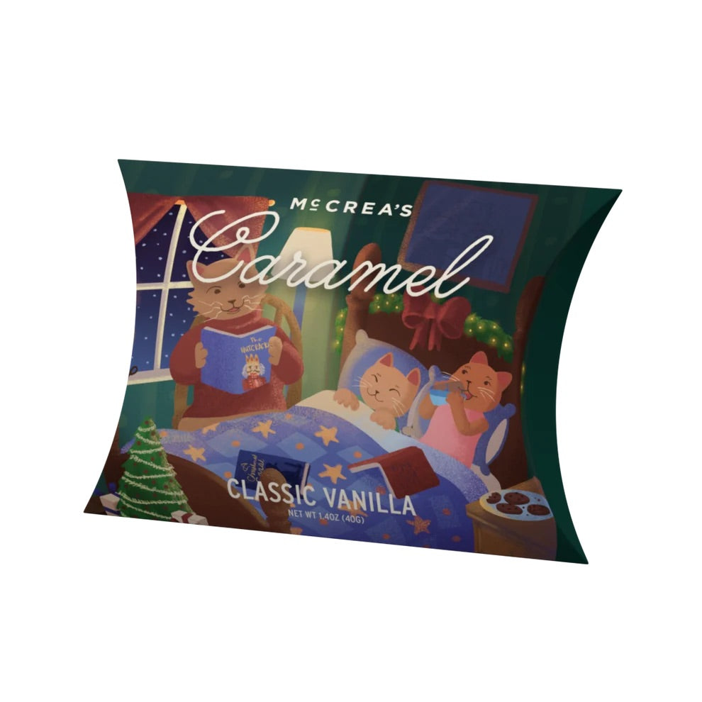 A decorative chocolate pillow pack featuring an illustrated winter scene with two cats reading under a blue starry blanket. The packaging reads &