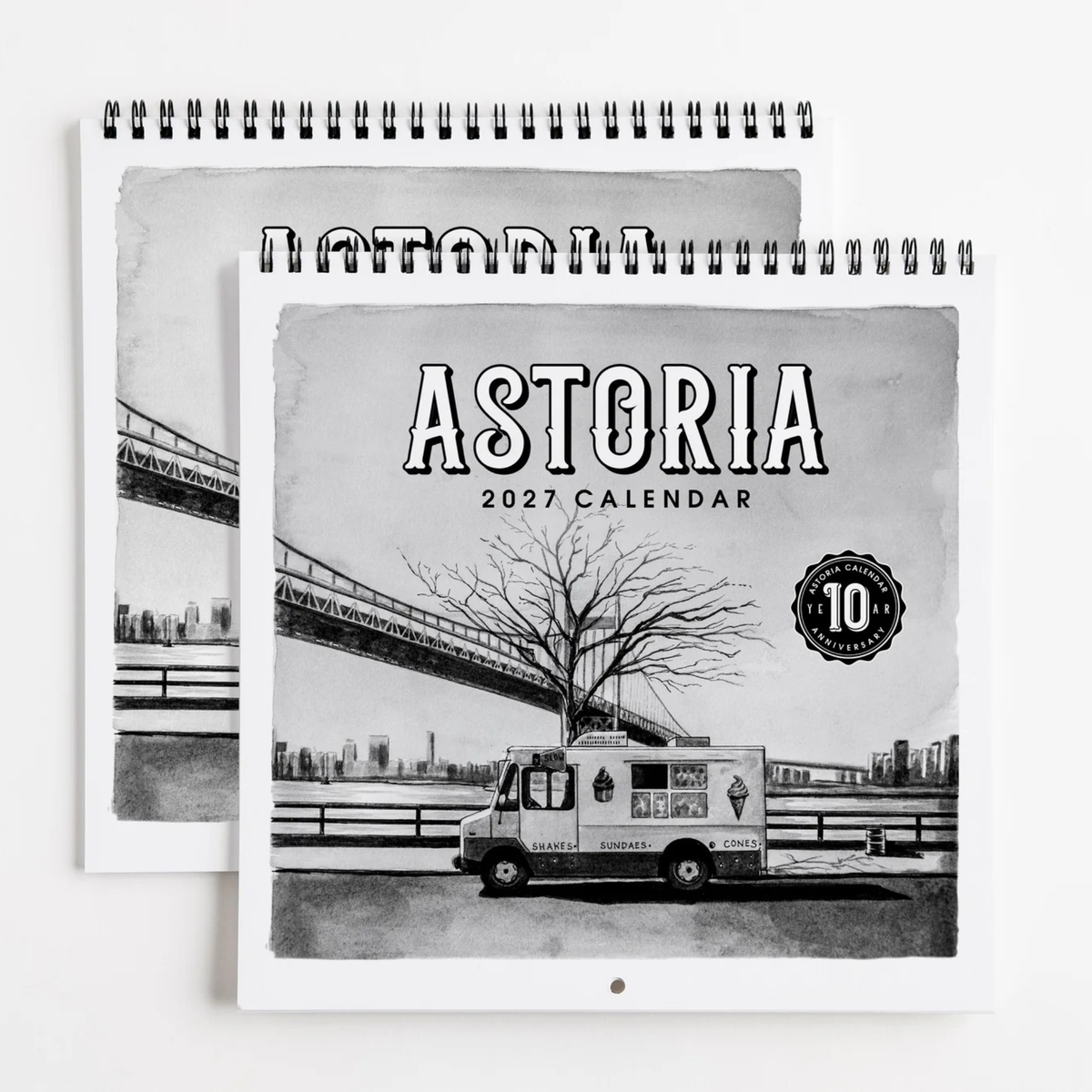A spiral-bound 2027 Astoria calendar shown in a stacked layout. The cover features a black-and-white illustration of an Astoria ice truck, a leafless tree, and a bridge over water, with the text 'ASTORIA 2027 CALENDAR' and a circular '10 Year Anniversary' badge.