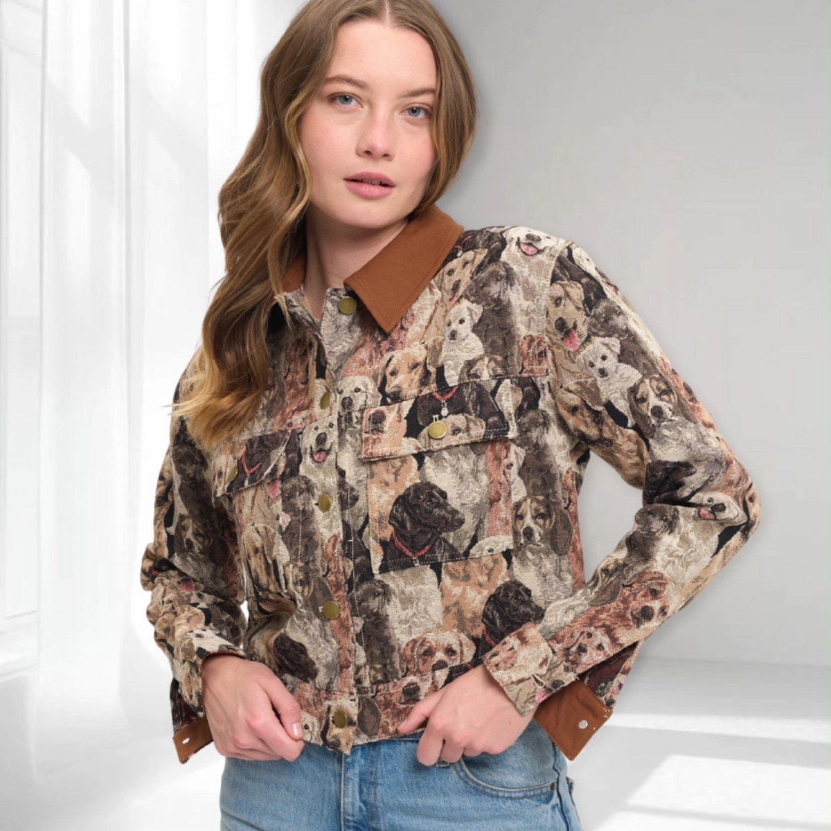 A woman wearing a long-sleeve button-up shirt with a detailed dog-print pattern and solid brown collar, cuffs, and pocket trim, paired with blue jeans.