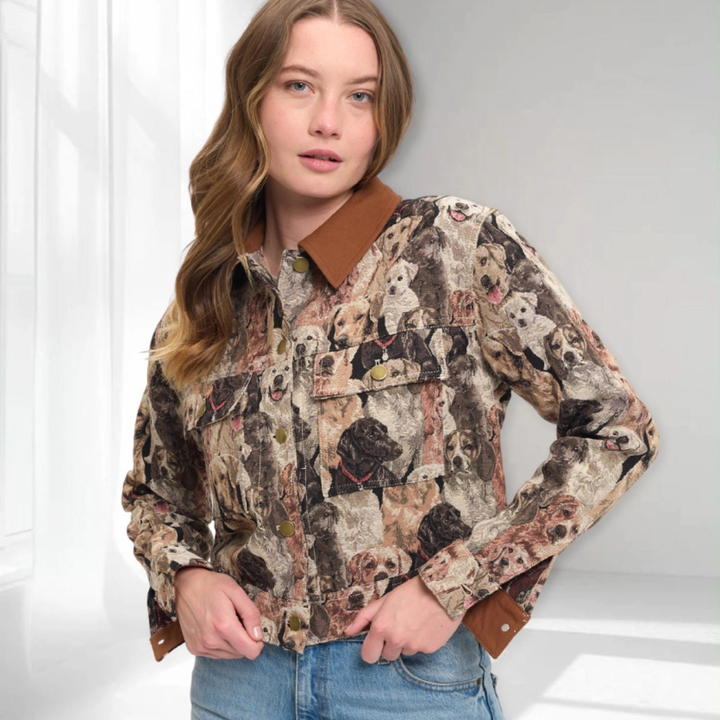 A woman wearing a long-sleeve button-up shirt with a detailed dog-print pattern and solid brown collar, cuffs, and pocket trim, paired with blue jeans.