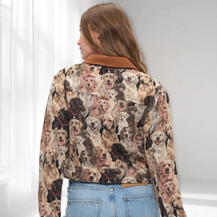 A woman viewed from behind wearing a cropped long-sleeve jacket with an all-over print of different dog faces, featuring a brown suede-like collar and back panel, paired with light blue jeans.