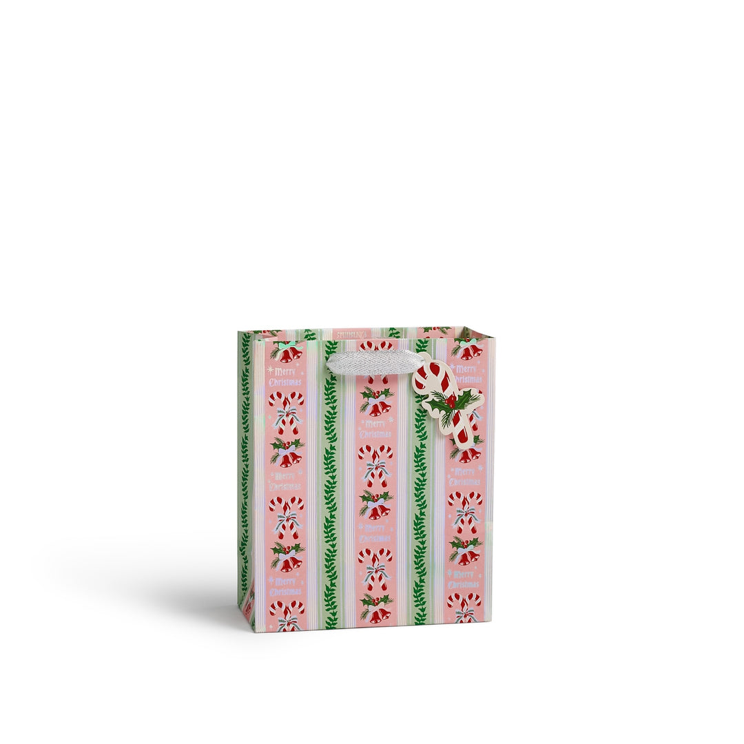 A small gift bag with a pink and white striped pattern, decorated with green pine branches and red candy canes, featuring a white bow on the handle, set against a plain white background.