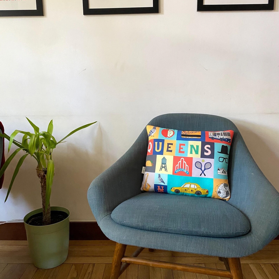 A colorful square throw pillow with a patchwork design spelling &