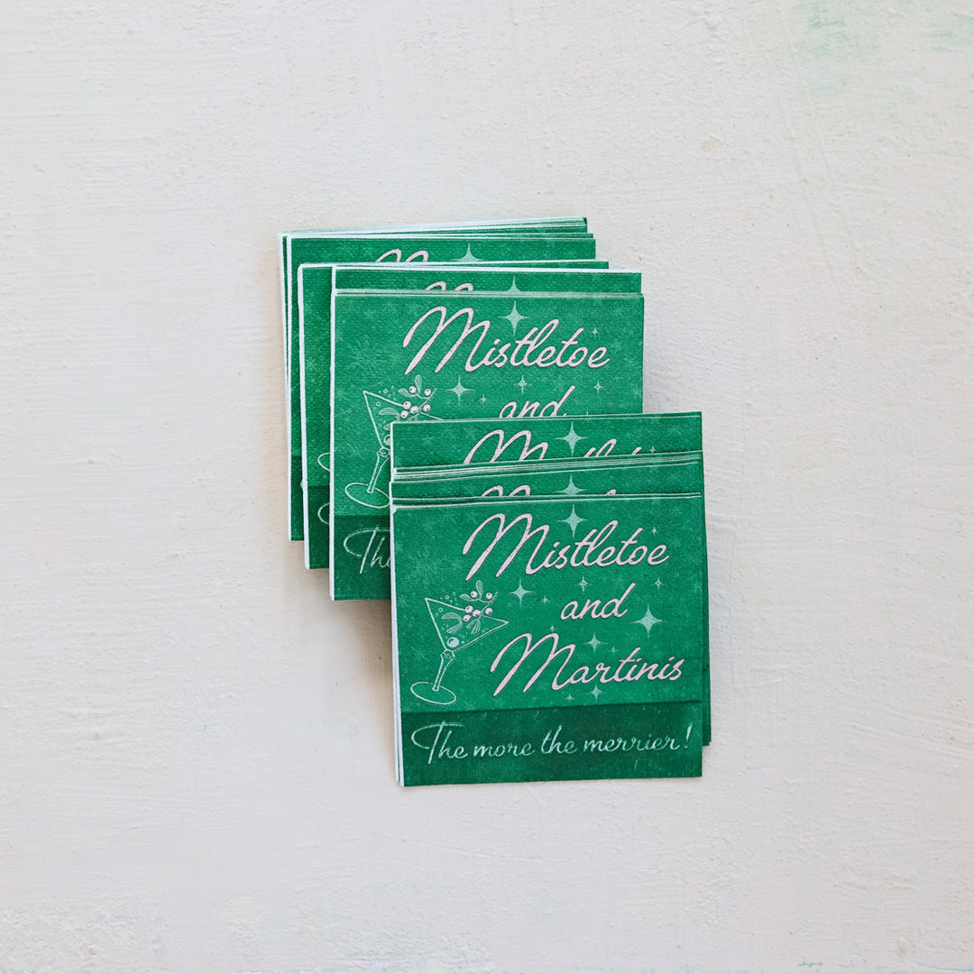 A stack of green cocktail-themed cards or napkins with white script text reading &