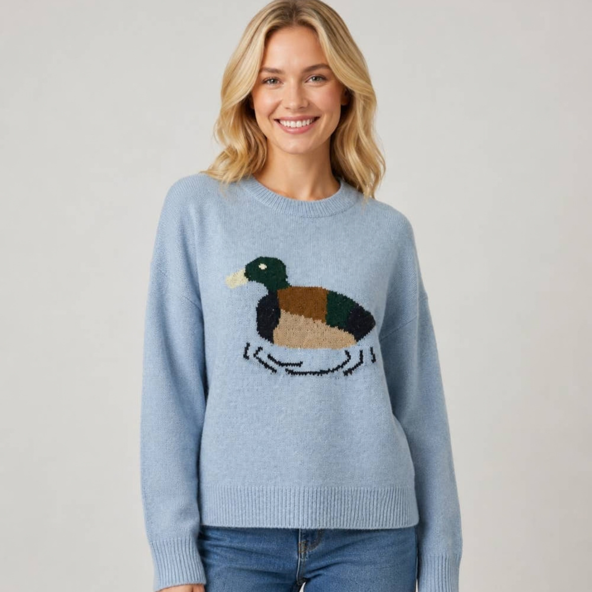 Woman wearing a blue sweater with a duck on it.