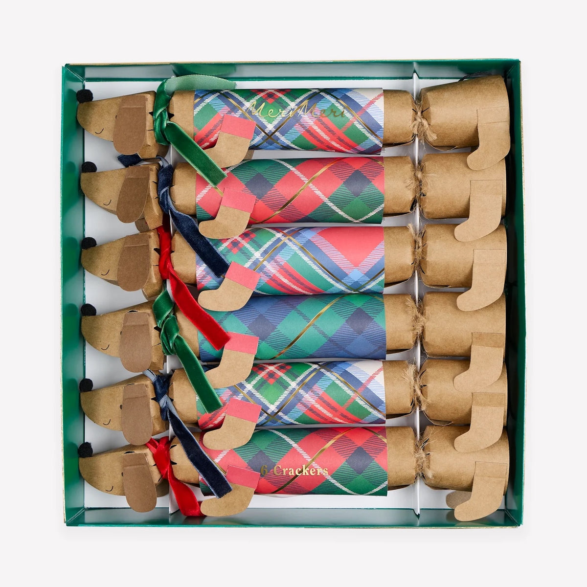 A boxed set of dachshund-shaped paper cracker ornaments with colorful plaid patterns and ribbon accents, arranged inside a green gift box on a light gray background.