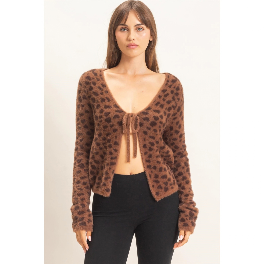 A woman modeling a brown fuzzy leopard-print cardigan with a tie-front detail and black pants, photographed against a plain light background.