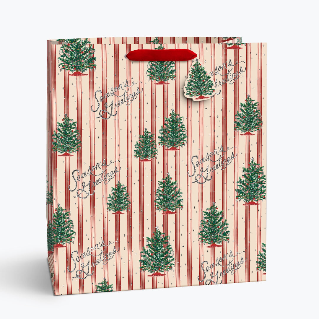 A Christmas-themed gift bag with a pink and red striped pattern, decorated with green pine trees and the words &