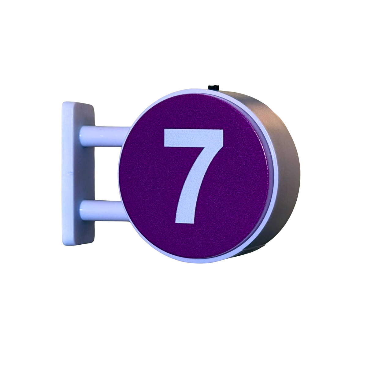 A circular purple sign with a large white number 7, mounted on a white bracket against a plain white background.