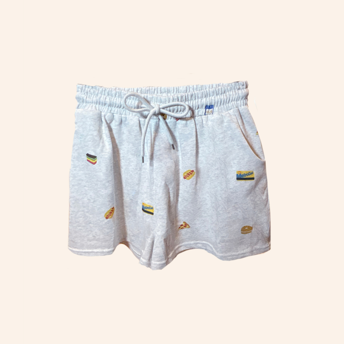 Light heather gray drawstring shorts with small colorful embroidered food motifs, displayed against a solid pale beige background.