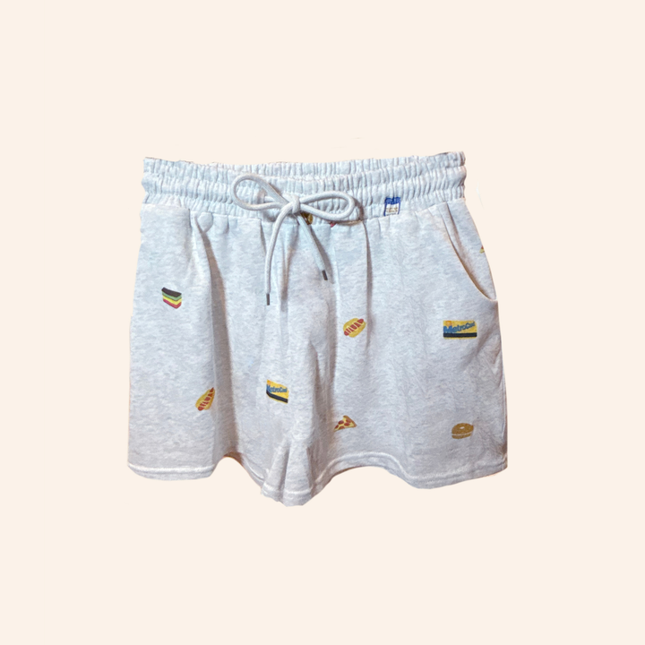 Light heather gray drawstring shorts with small colorful embroidered food motifs, displayed against a solid pale beige background.