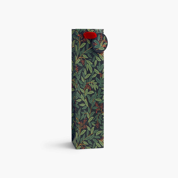 A tall rectangular carton with a dark green botanical pattern of leaves and red berries, featuring a small red circular label near the top, shown on a clean white background.